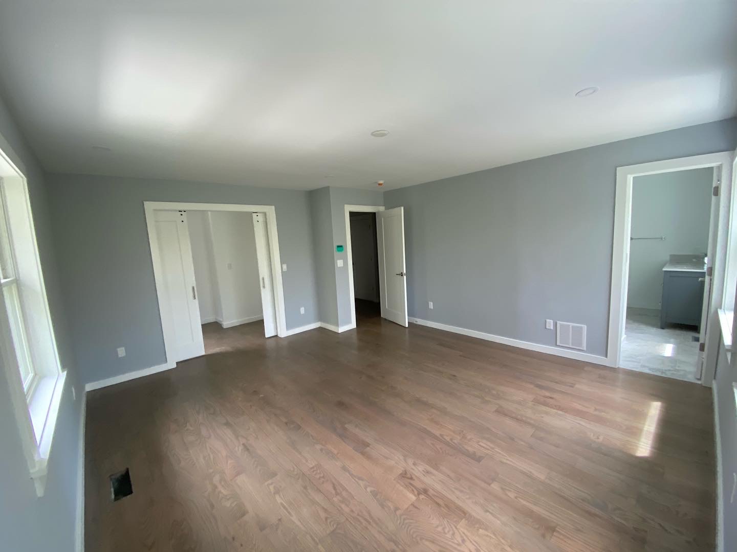 Bedroom repainted in soft gray with clean white trim and hardwood floor